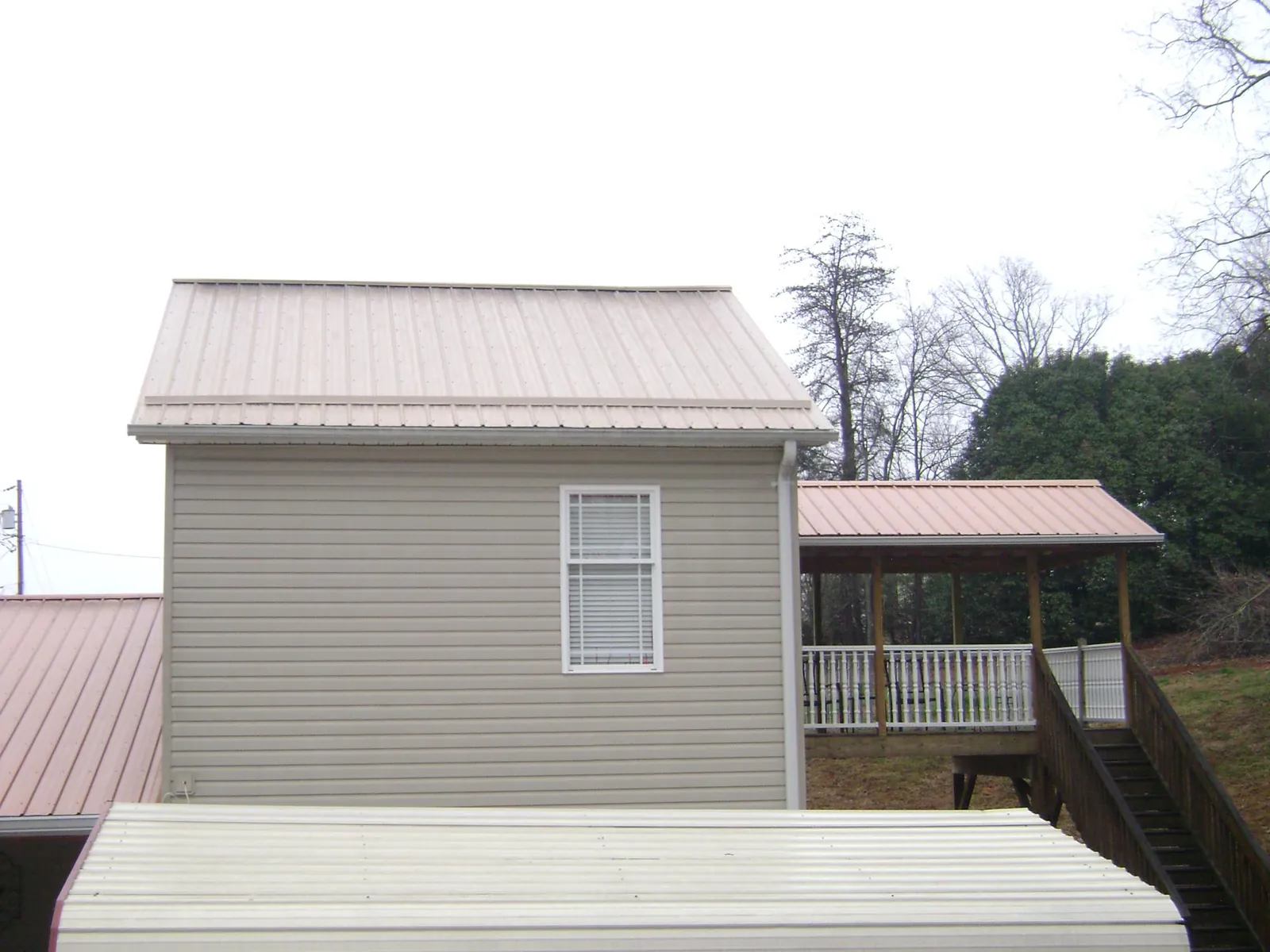 Tan metal roofs on a two story addition and attached porch, from a Roof Replacement job in Peshastin